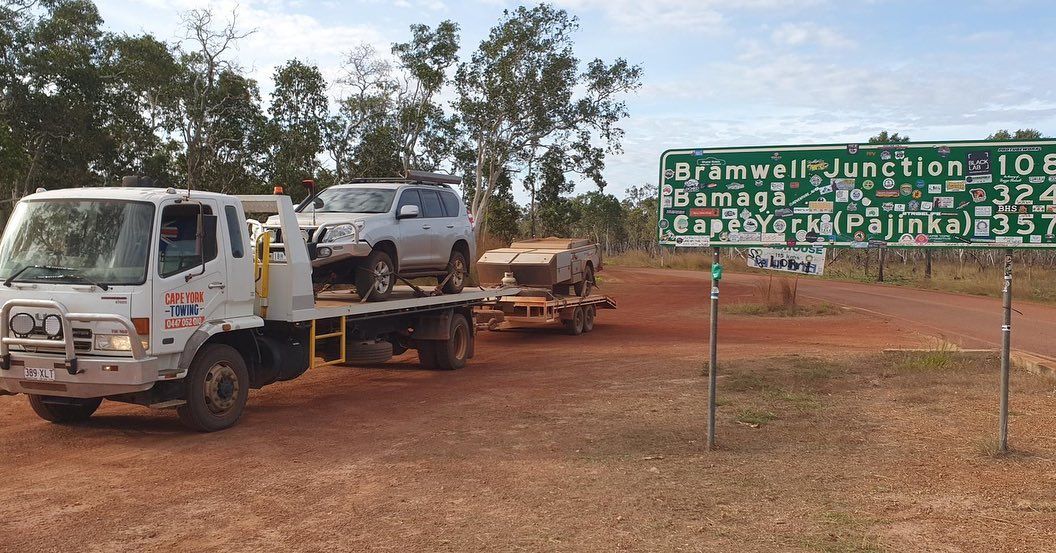 Two Cars Are Being Towed by a Tow Truck in a Dirt Field — Cape York Towing & Transport in Georgetown, QLD