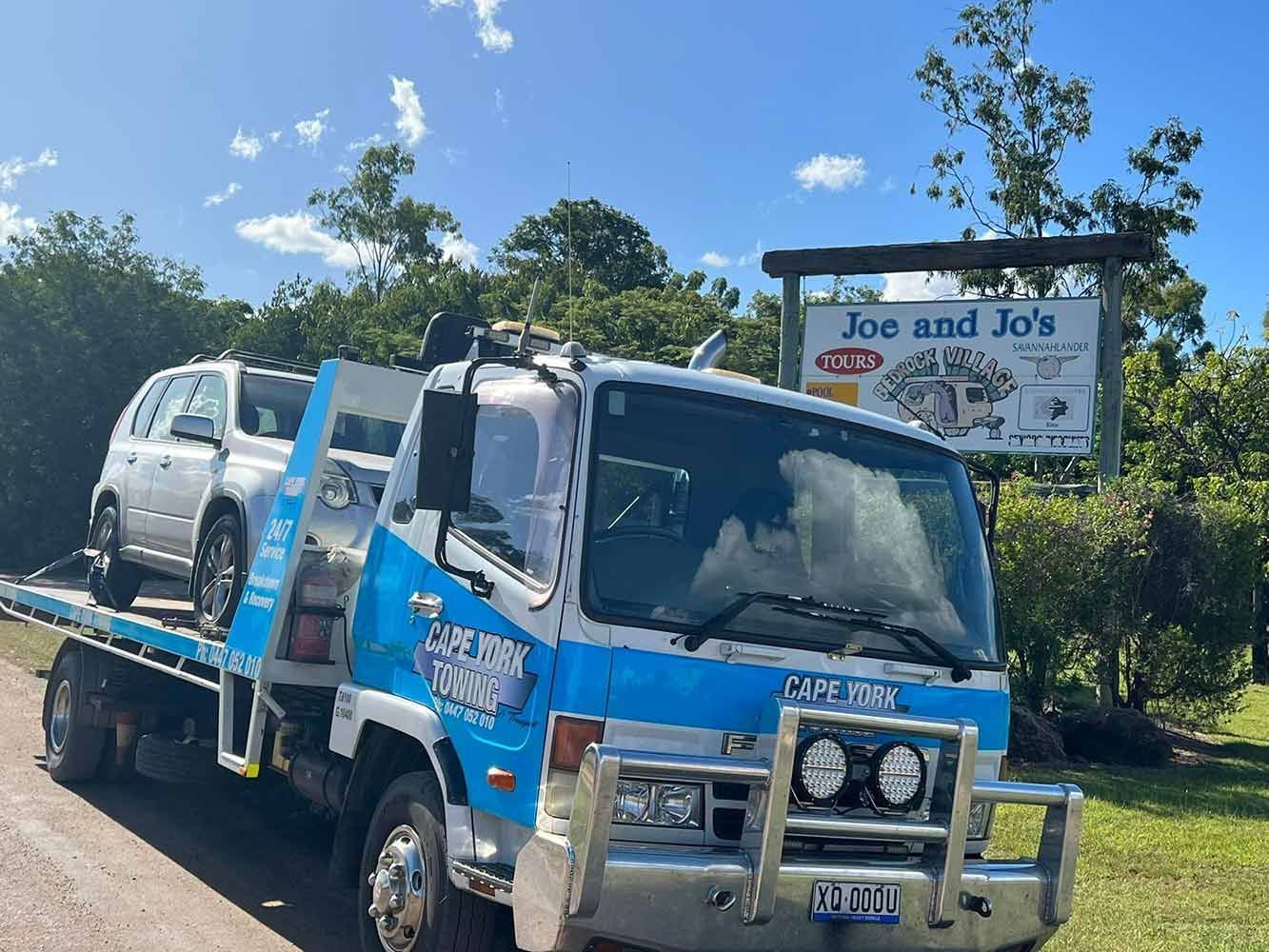 A Tow Truck With a Car on the Back is Parked on the Side of the Road — Cape York Towing in Rockhampton, QLD