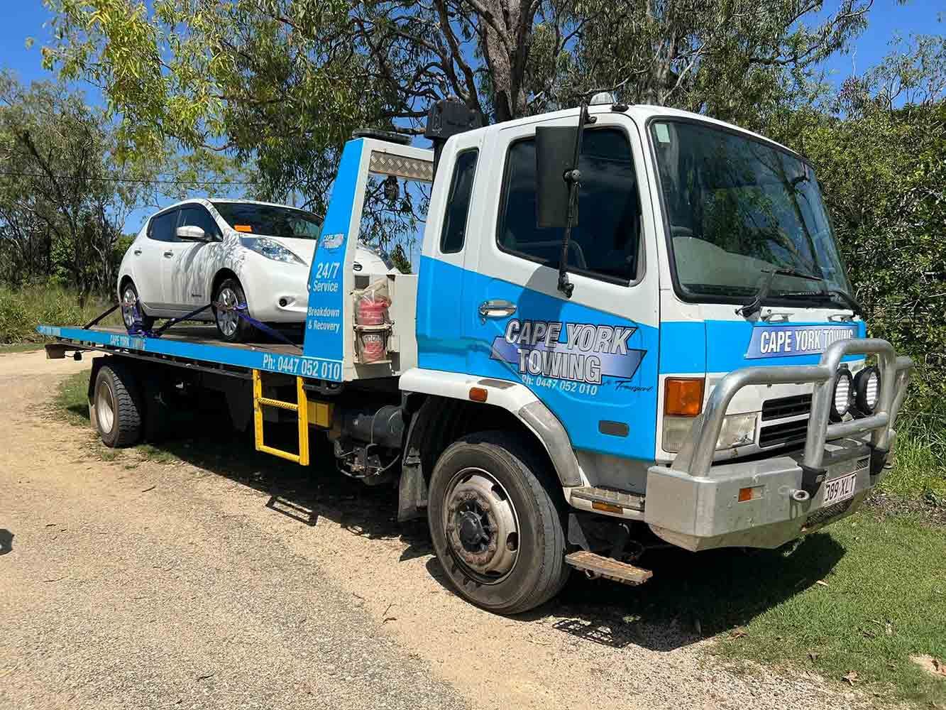 A Tow Truck With a Car on the Back is Parked on a Dirt Road — Cape York Towing & Transport in Bamaga, QLD
