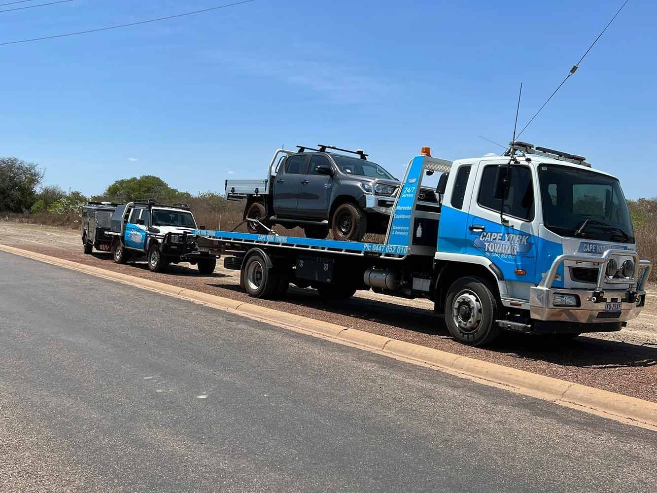 A Tow Truck is Carrying a Row of Trucks Down a Road — Cape York Towing & Transport in Sydney, NSW