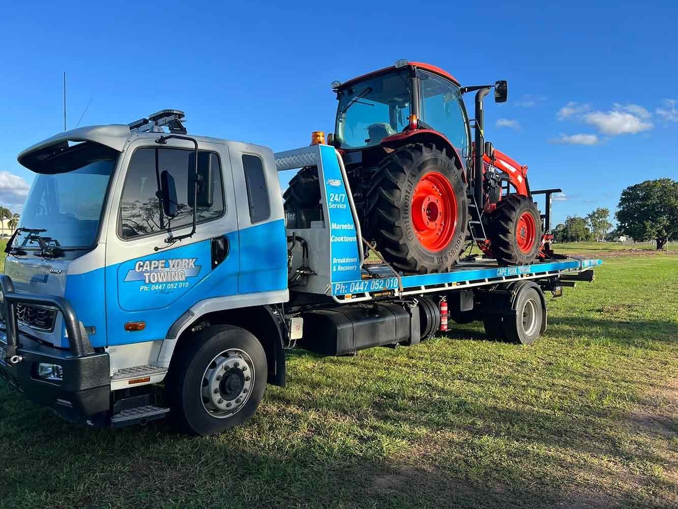 A Tow Truck is Towing a Tractor in a Field — Cape York Towing & Transport in Mount Molloy, QLD