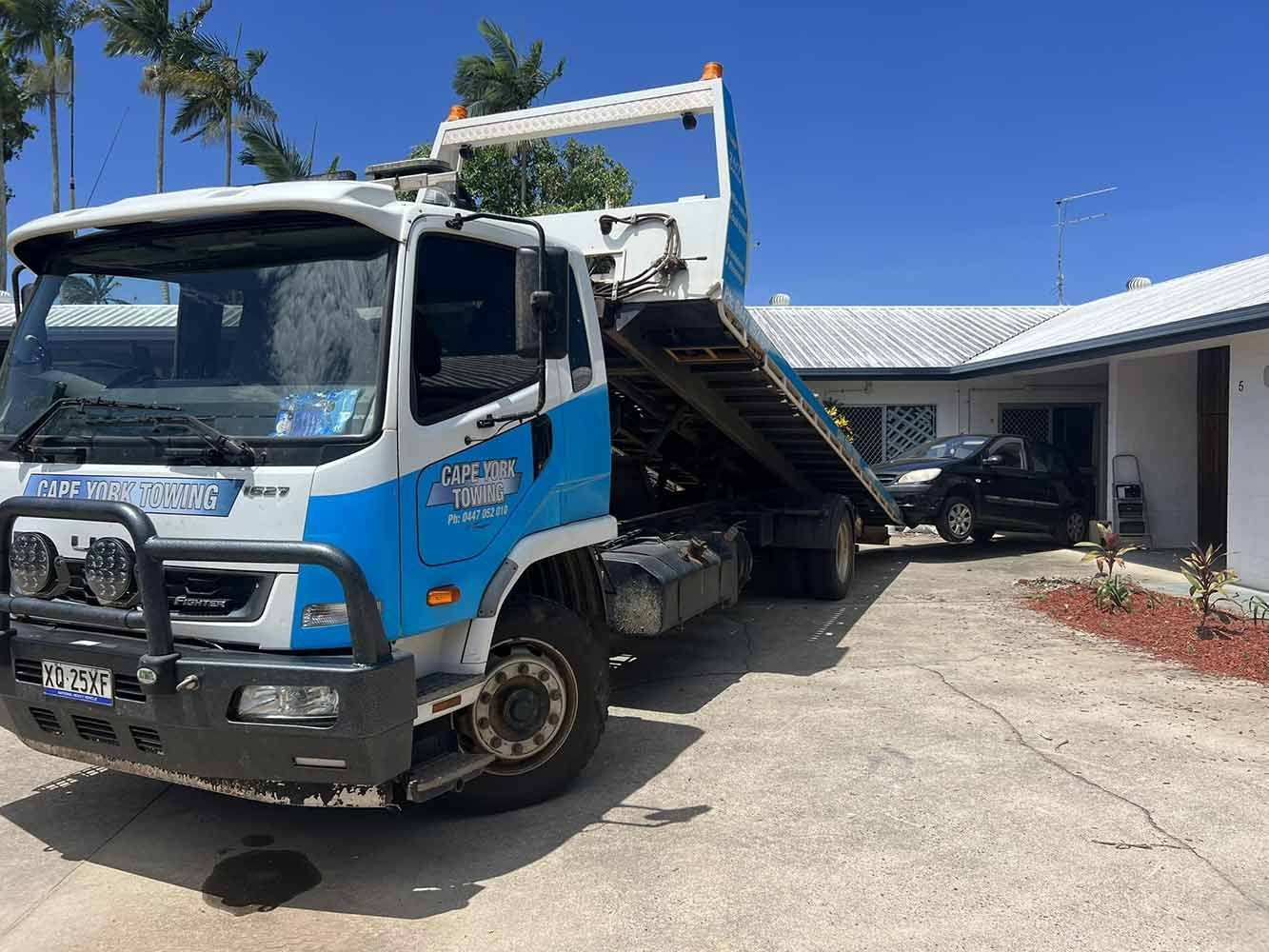 A Blue and White Tow Truck is Parked in Front of a House — Cape York Towing & Transport in Cape York, QLD