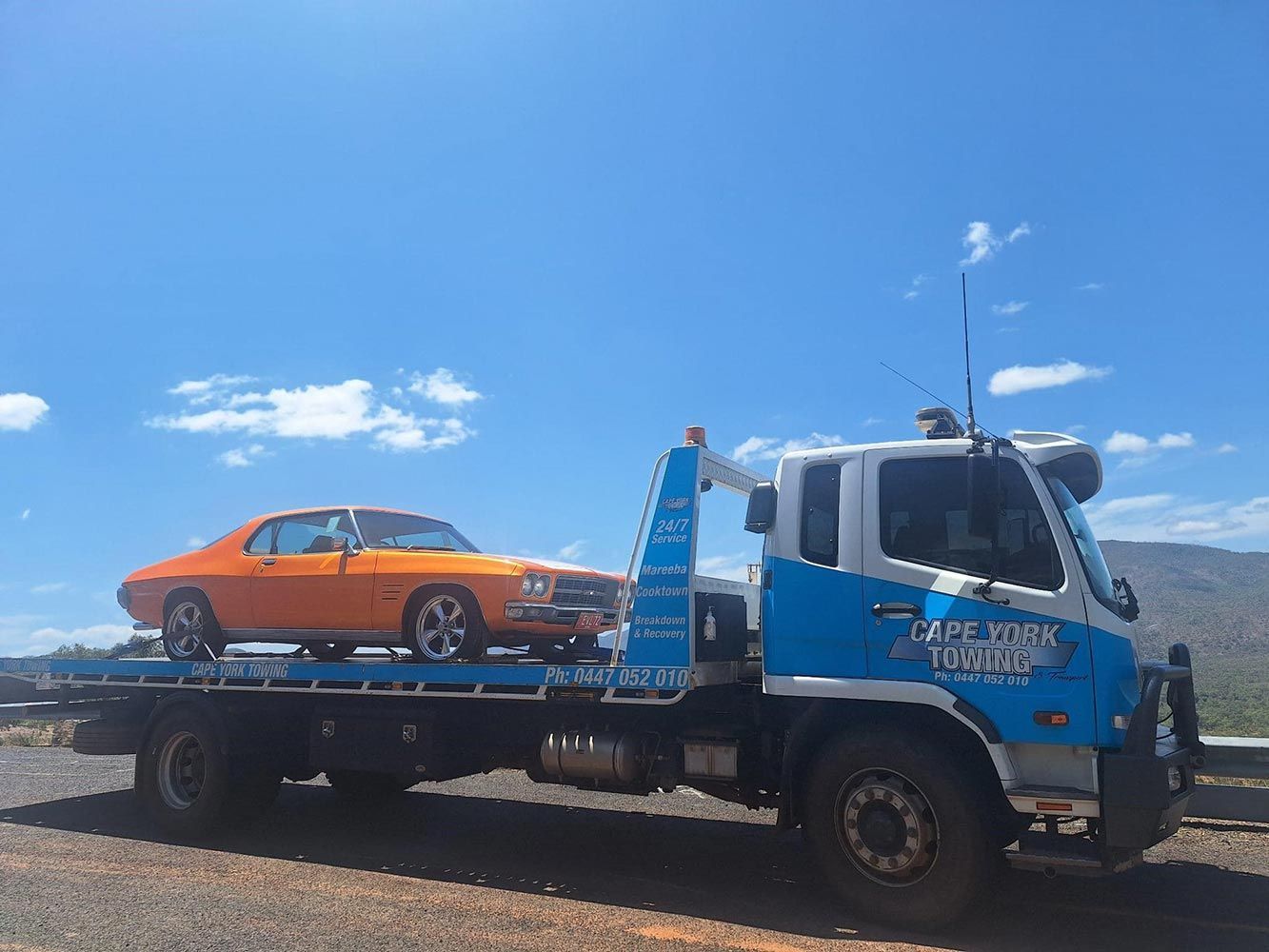 An Orange Car is Being Towed by a Tow Truck — Cape York Towing & Transport in Karumba, QLD