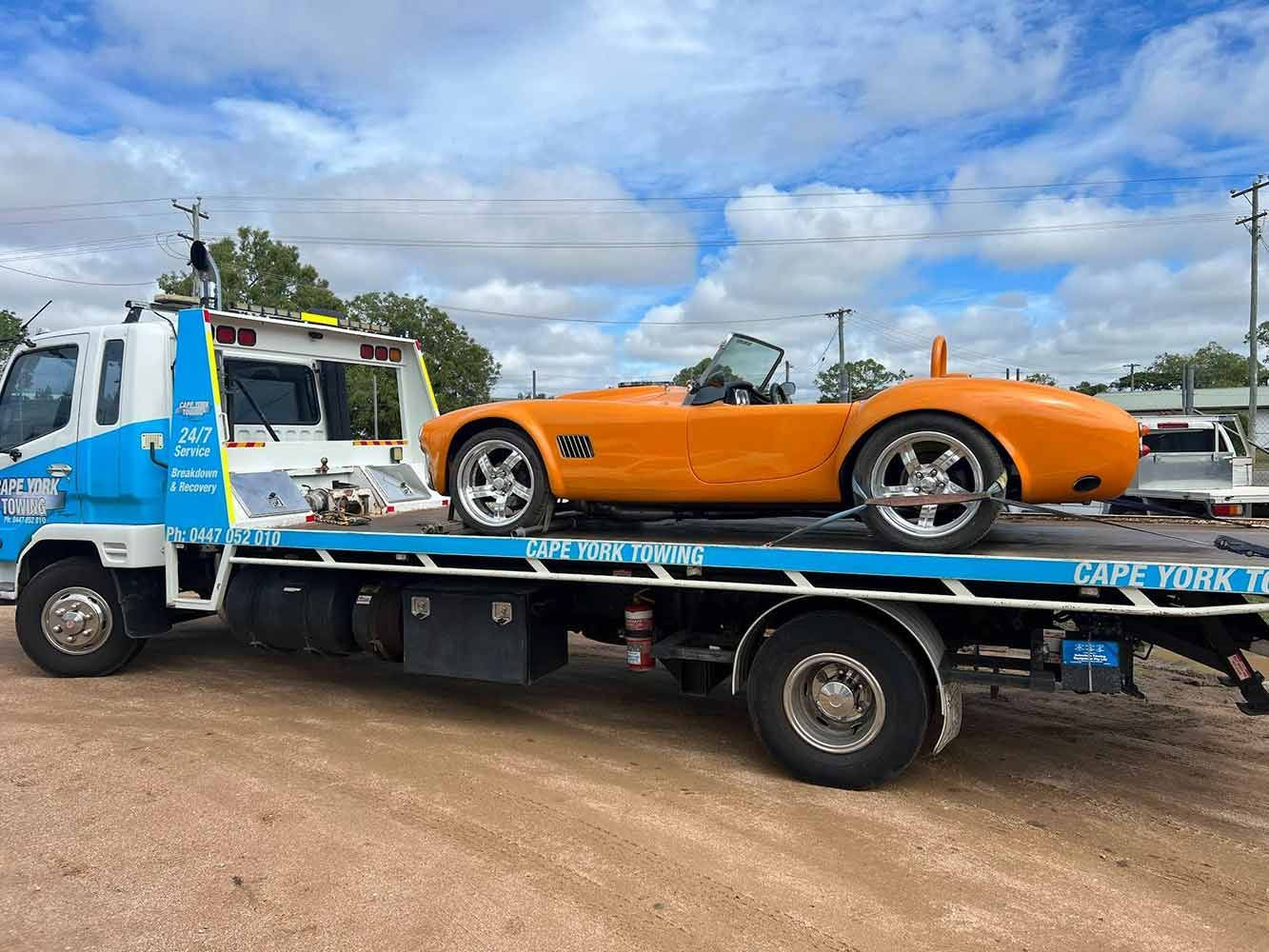 An Orange Sports Car is Being Towed by a Tow Truck — Cape York Towing & Transport in Weipa, QLD