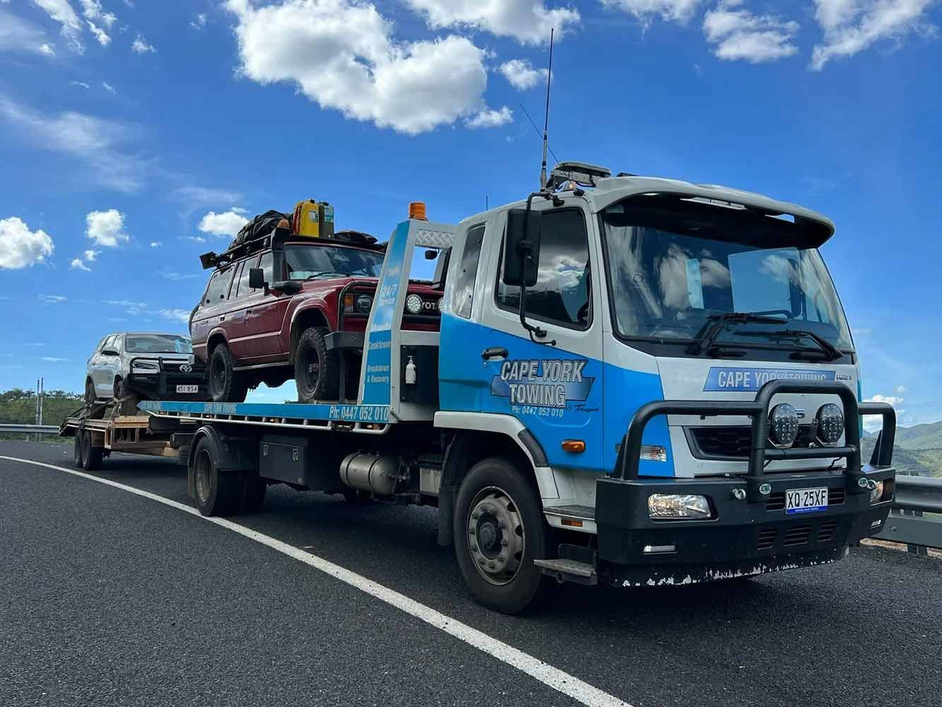 A Tow Truck is Carrying Two Cars on a Highway — Cape York Towing & Transport in Ravenshoe, QLD