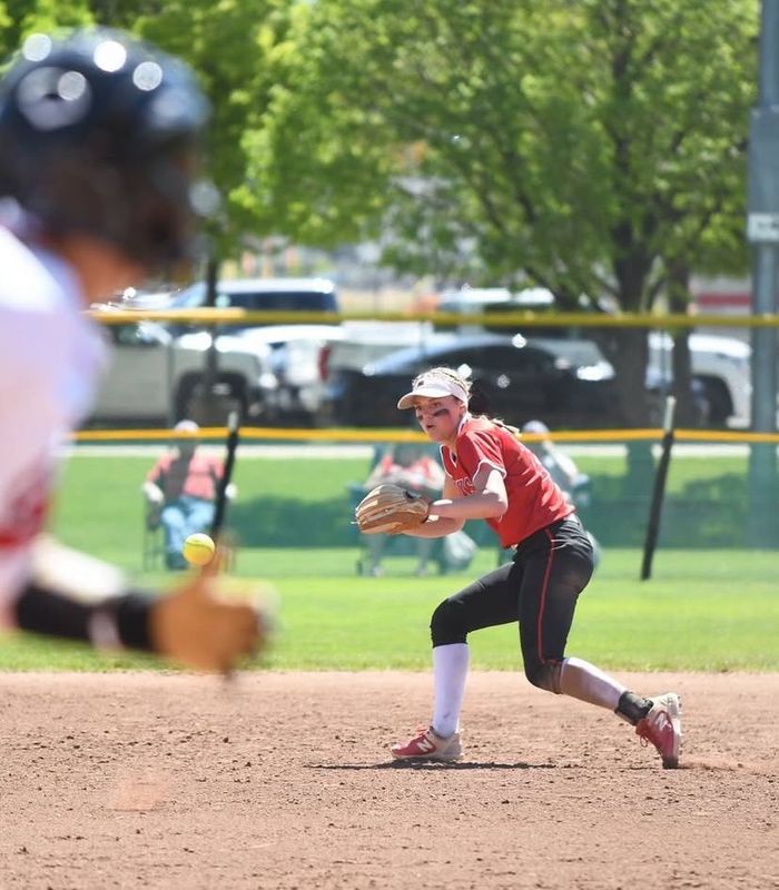 Girl in a softball field in stance ready to catch a ball