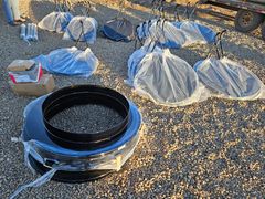 Buckets and tarps arranged on gravel beside a black plastic tub filled with water.