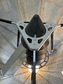 Close-up of a black cone-shaped device mounted on a silver triangular frame inside a metallic enclosure