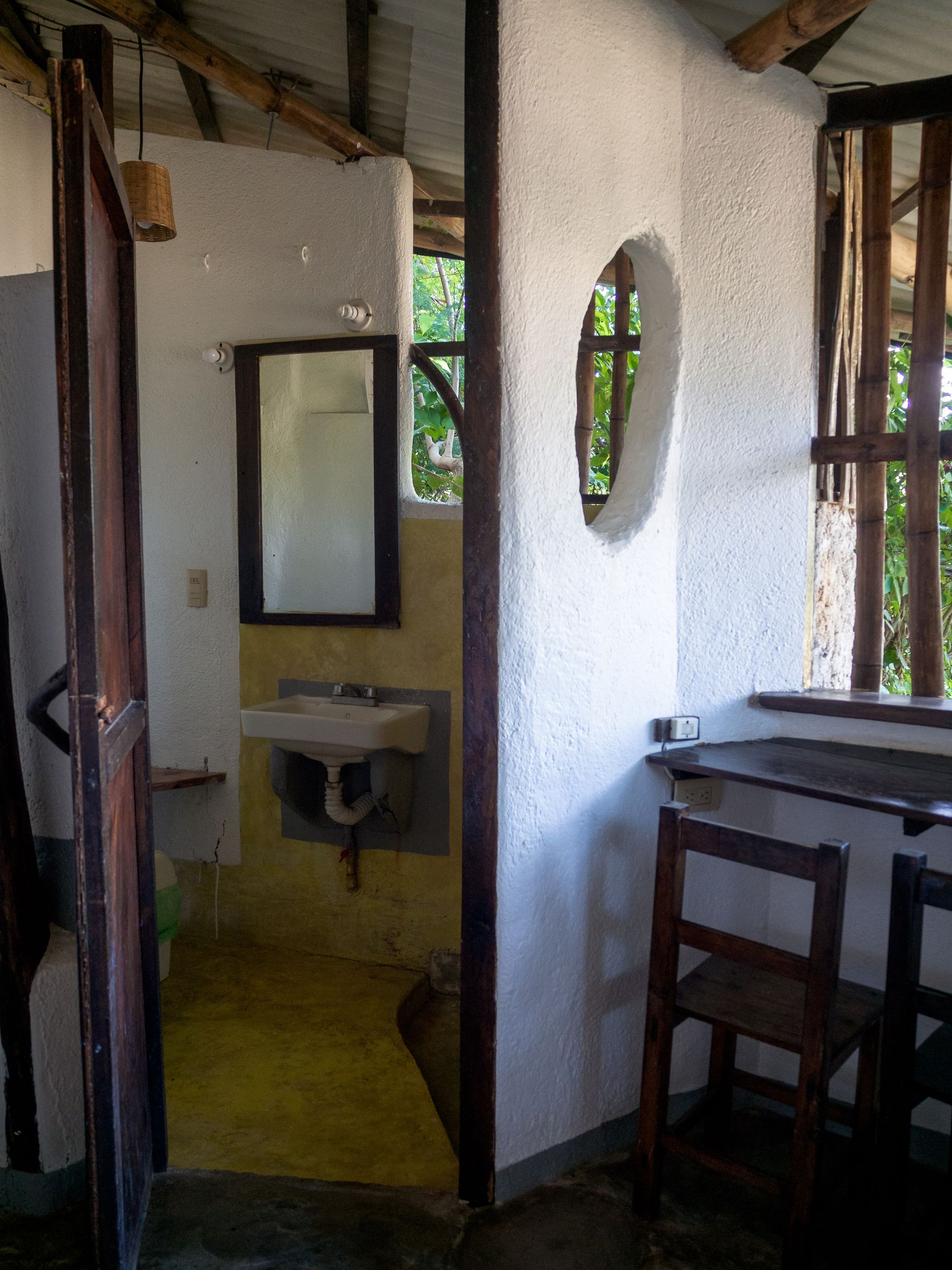 Interior con puerta de acceso a un baño y ventana con vistas a la vegetación en posada del arquitecto
