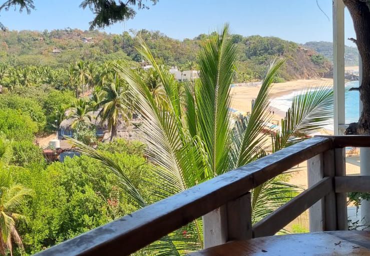 Vista desde un balcón de madera con vistas a la playa y el océano en posada del arquitecto