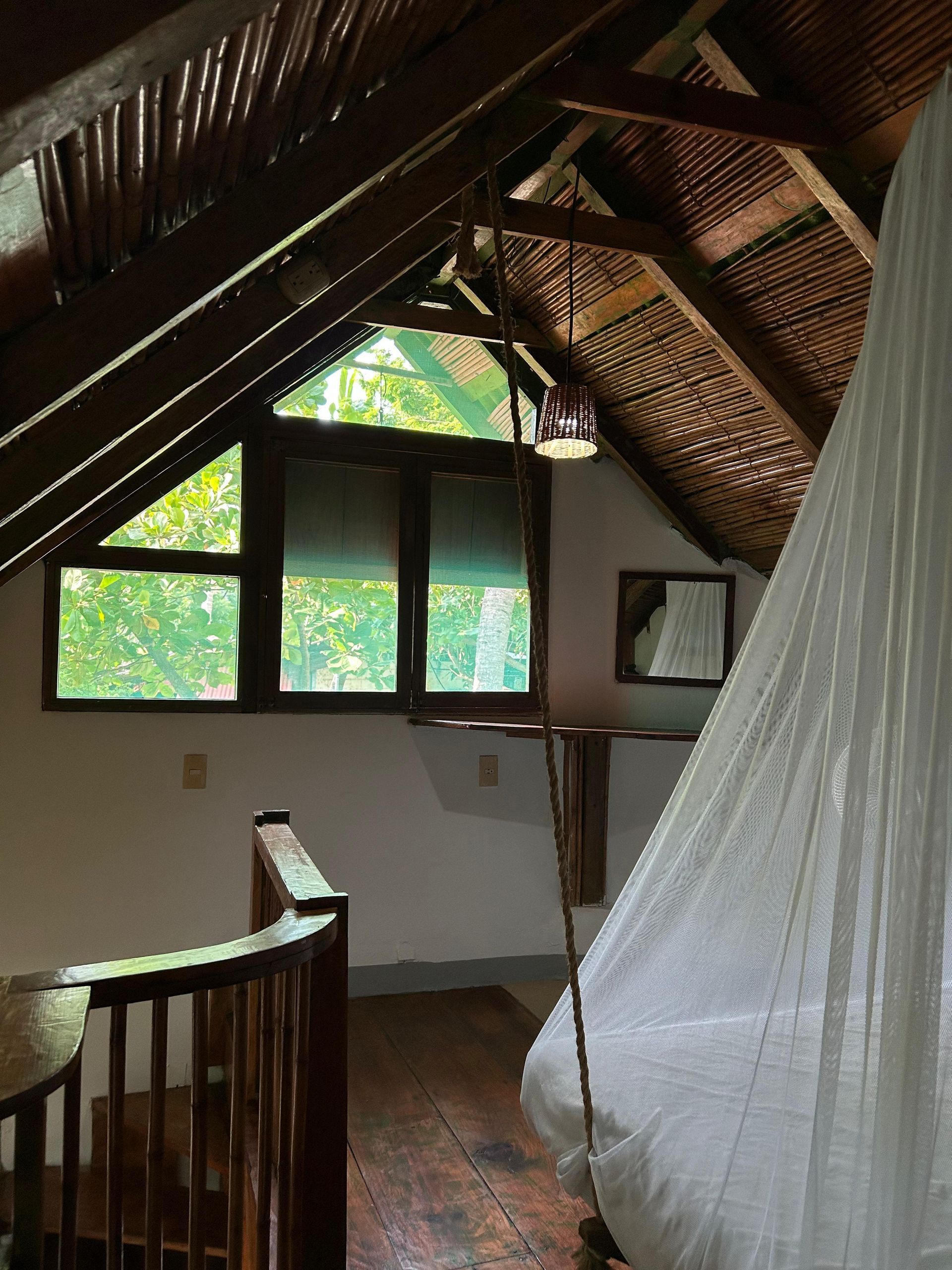 Acogedora habitación abuhardillada con vigas de madera y escalera de caracol en posada del arquitecto en mazunte, oaxaca