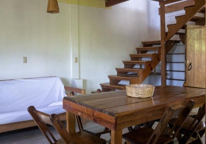 Mesa de comedor de madera con sillas, sofá en posada del arquitecto en mazunte, oaxaca