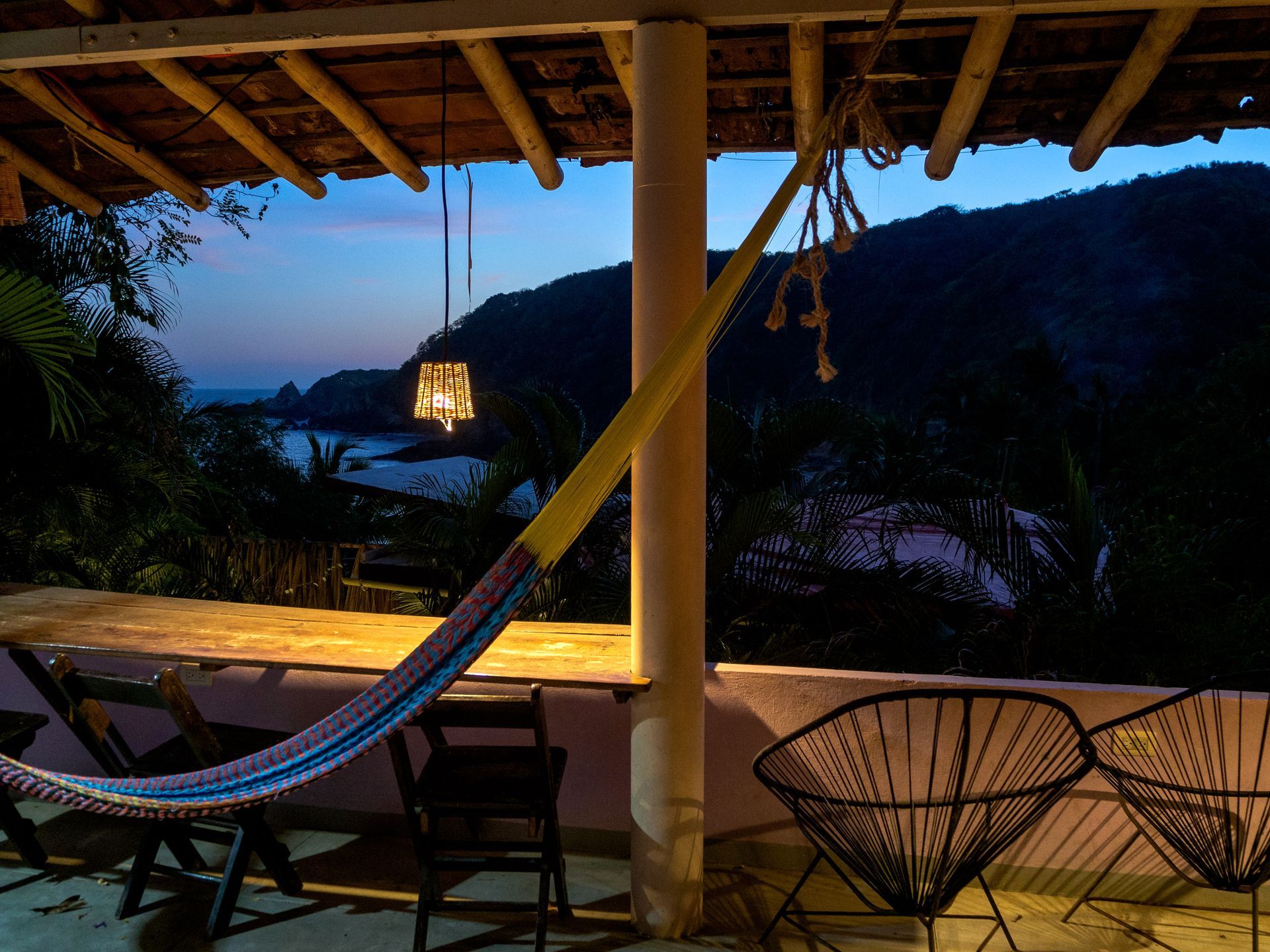 Patio con hamaca y sillas con vistas a una bahía al atardecer en mazunte, oaxaca