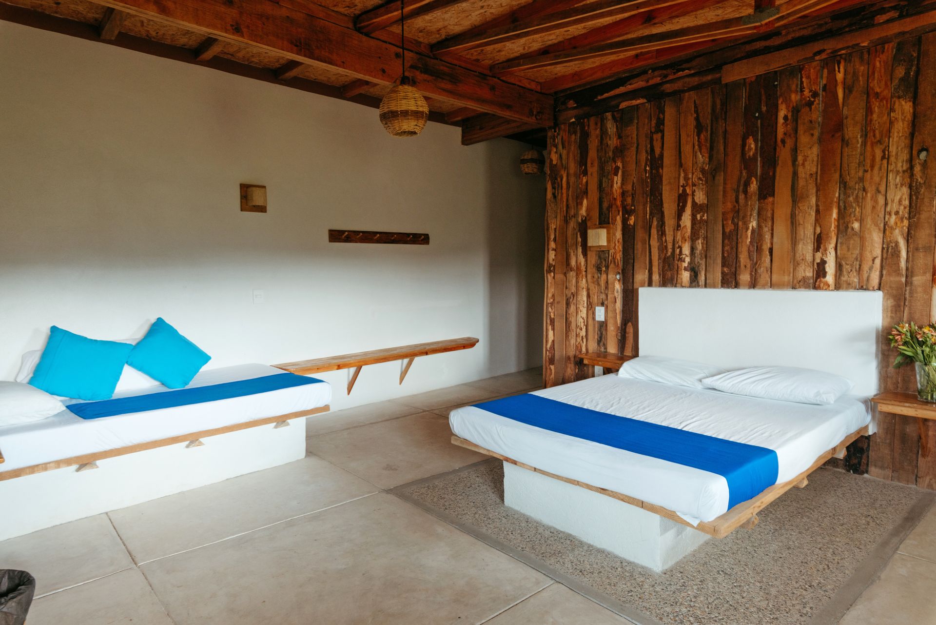 Dormitorio con camas blancas y paneles de madera en posada del arquitecto en mazunte, oaxaca