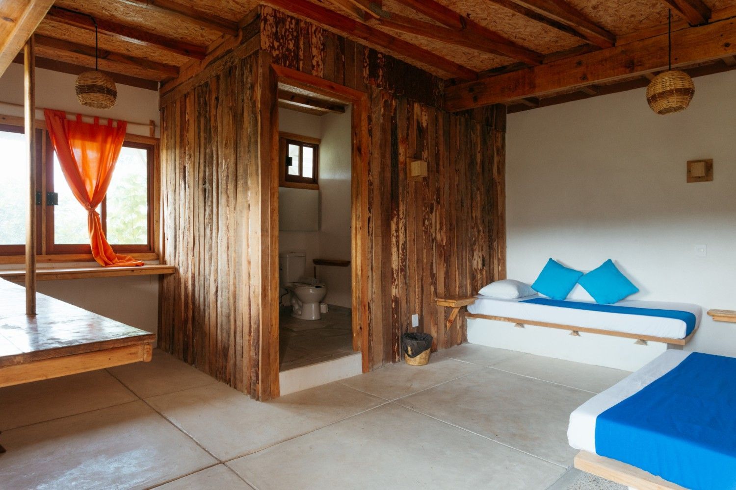 Interior de madera con camas y baño en posada del arquitecto en mazunte, oaxaca