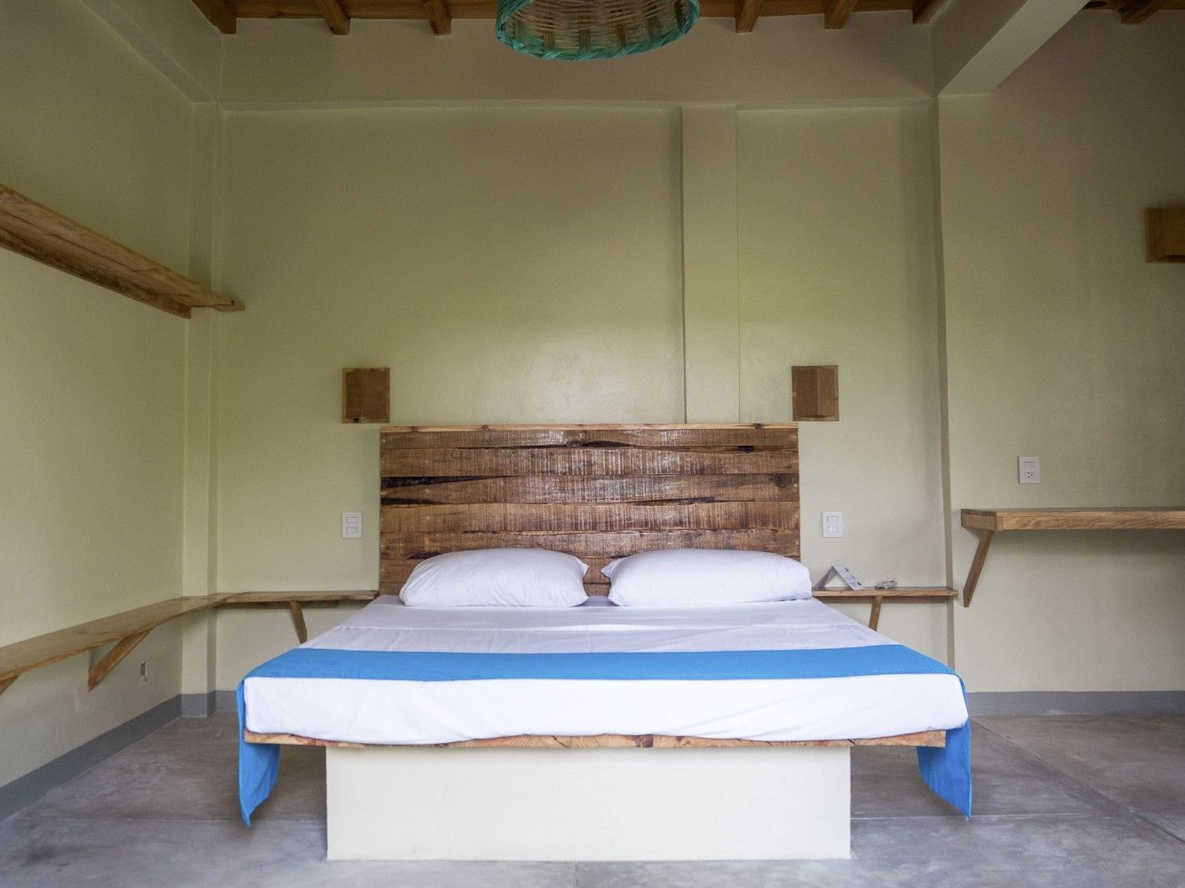 Dormitorio con cama y cabecero de madera, en posada del arquitecto en mazunte, oaxaca