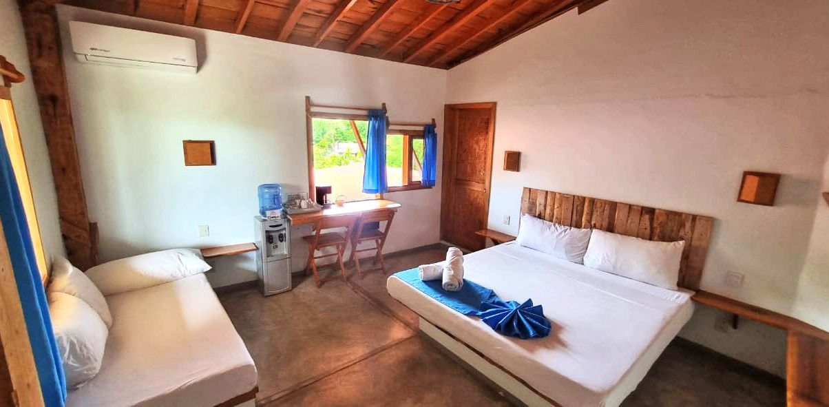 Dormitorio con cama, sofá, escritorio y ventana en posada del arquitecto en mazunte, oaxaca