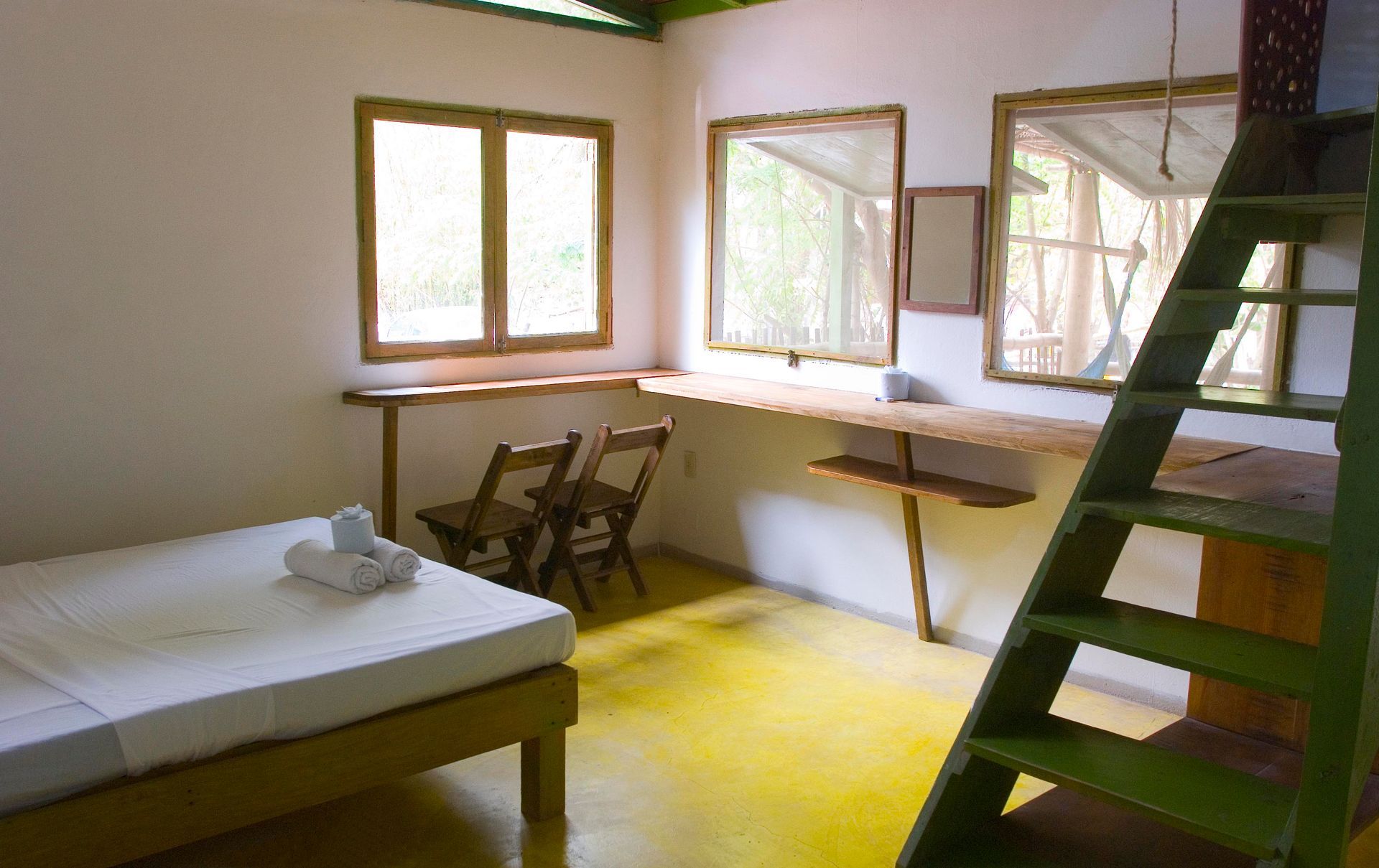 Habitación interior con cama, escritorio y dos sillas en posada del arquitecto en mazunte, oaxaca