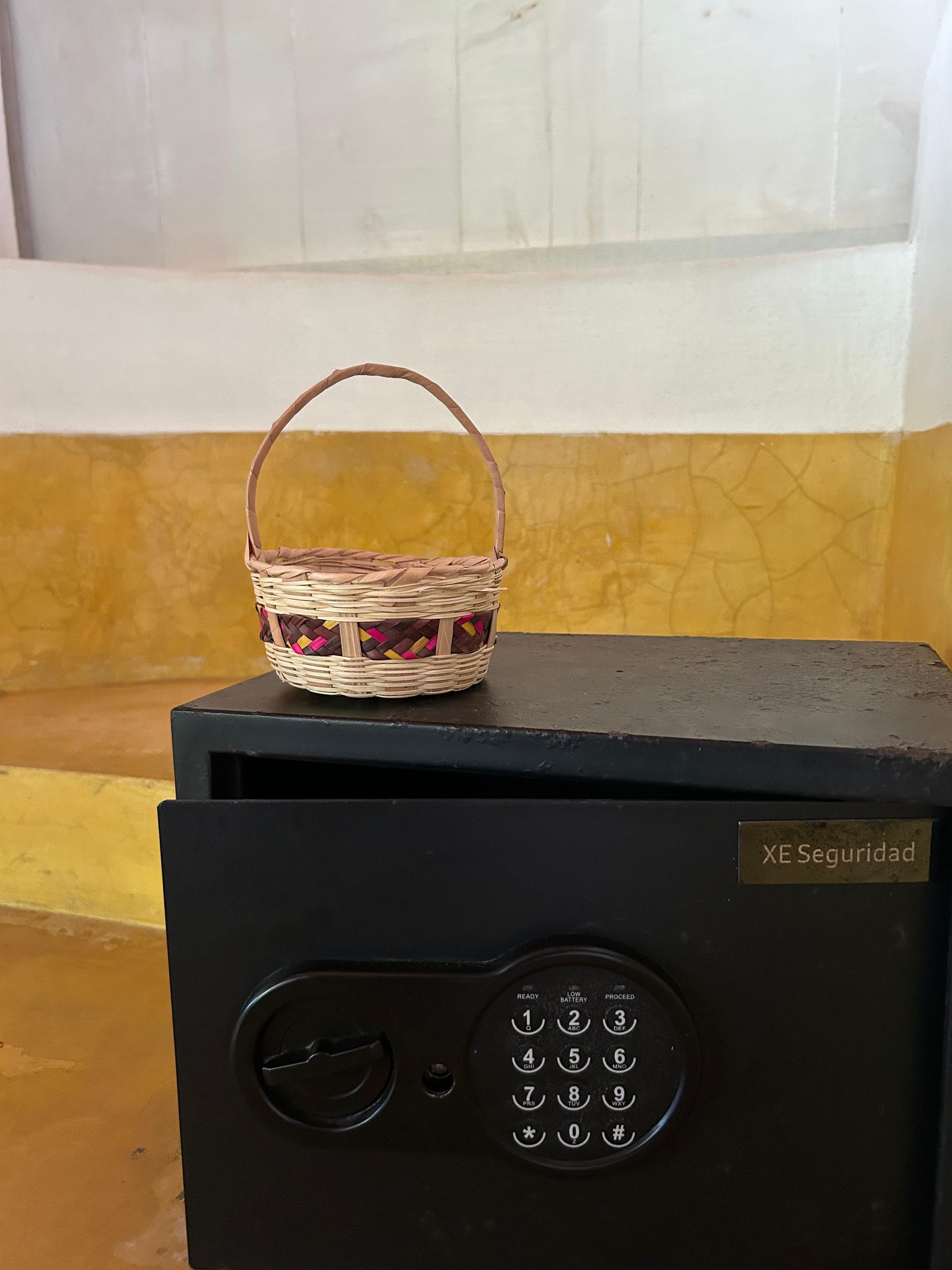 Una pequeña cesta con asa descansa sobre una caja fuerte en posada del arquitecto en mazunte, oaxaca