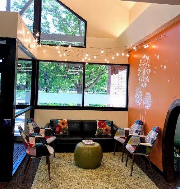 A living room with a couch and chairs and a green ottoman