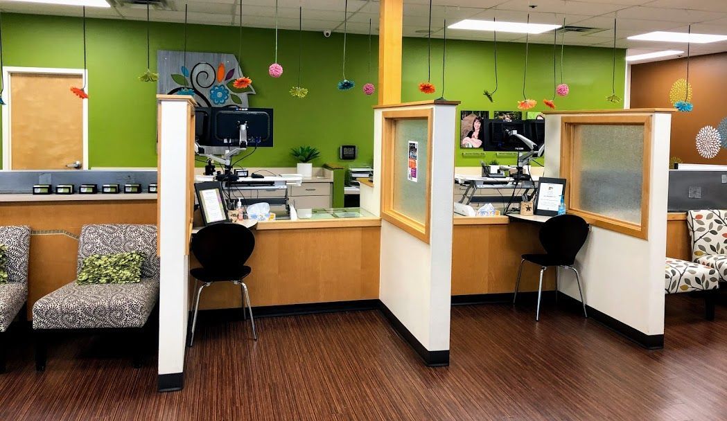 A waiting room with cubicles and chairs and a green wall.