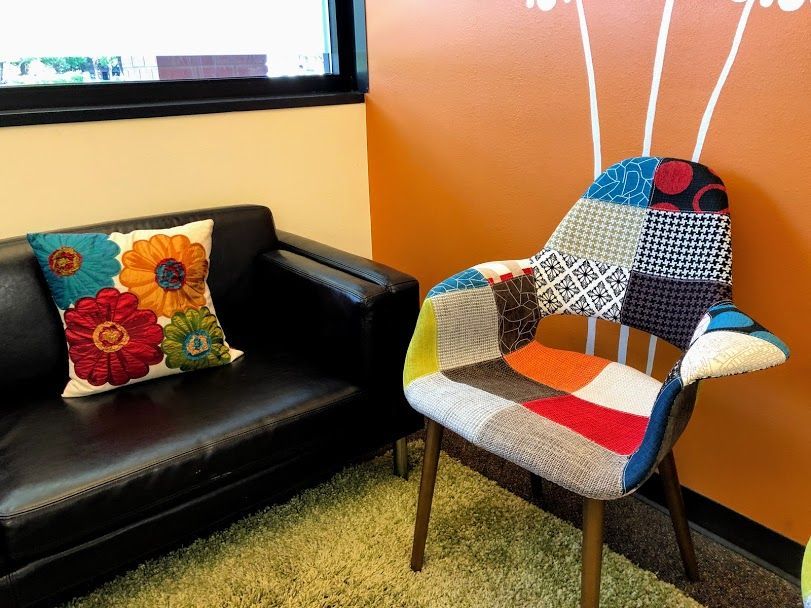 A colorful chair is sitting next to a couch in a room.