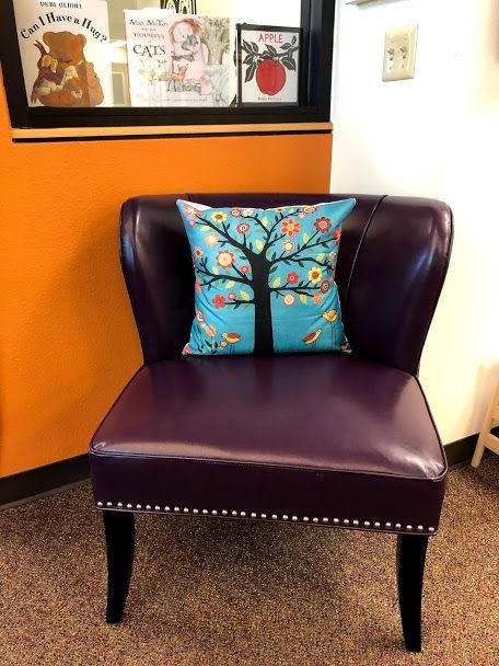 A purple chair with a blue pillow on it