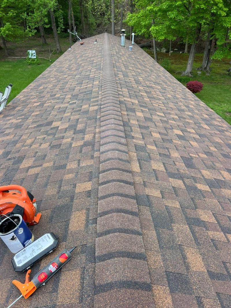 A long brown roof with tools lying on its side and trees in the background.