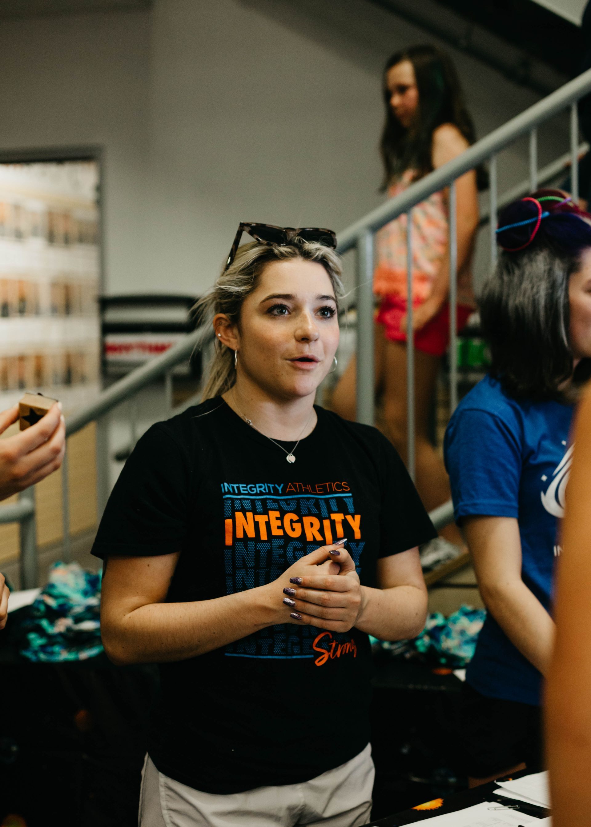 A woman wearing a black shirt that says integrity is standing in front of a group of people.