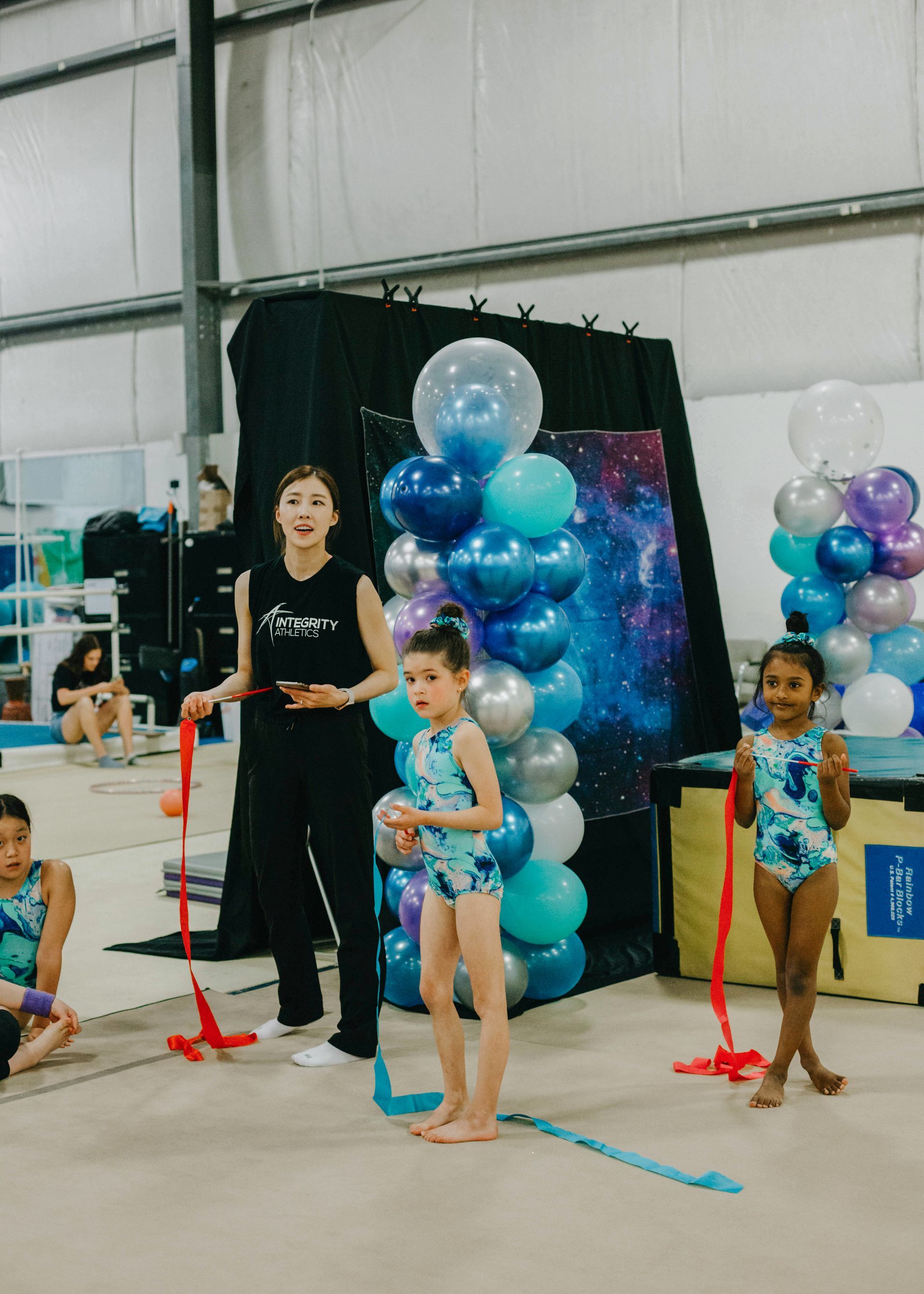 A group of young girls are practicing rhythmic gymnastics in a gym.