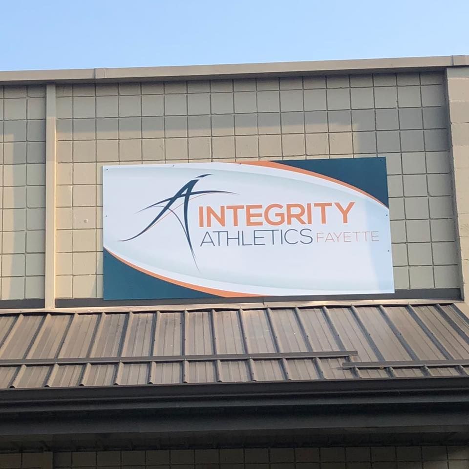 Integrity Athletics sign on a beige building with a teal accent panel and metal roof