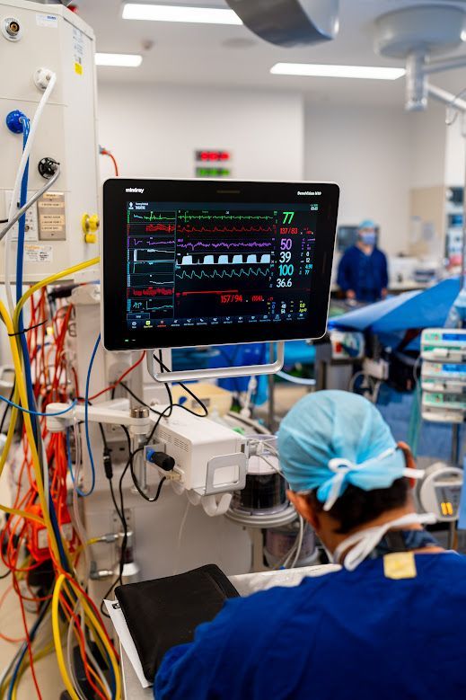 Hospital operating room with a patient monitor and surgical staff in blue scrubs and masks