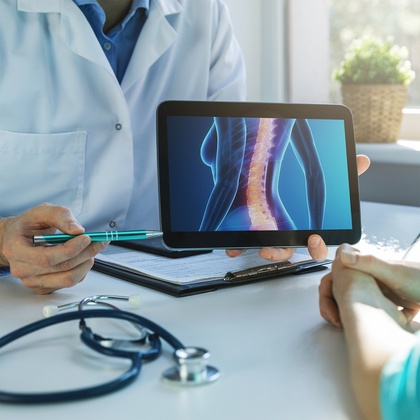 Doctor reviewing a spine scan on a tablet with a patient in a clinic