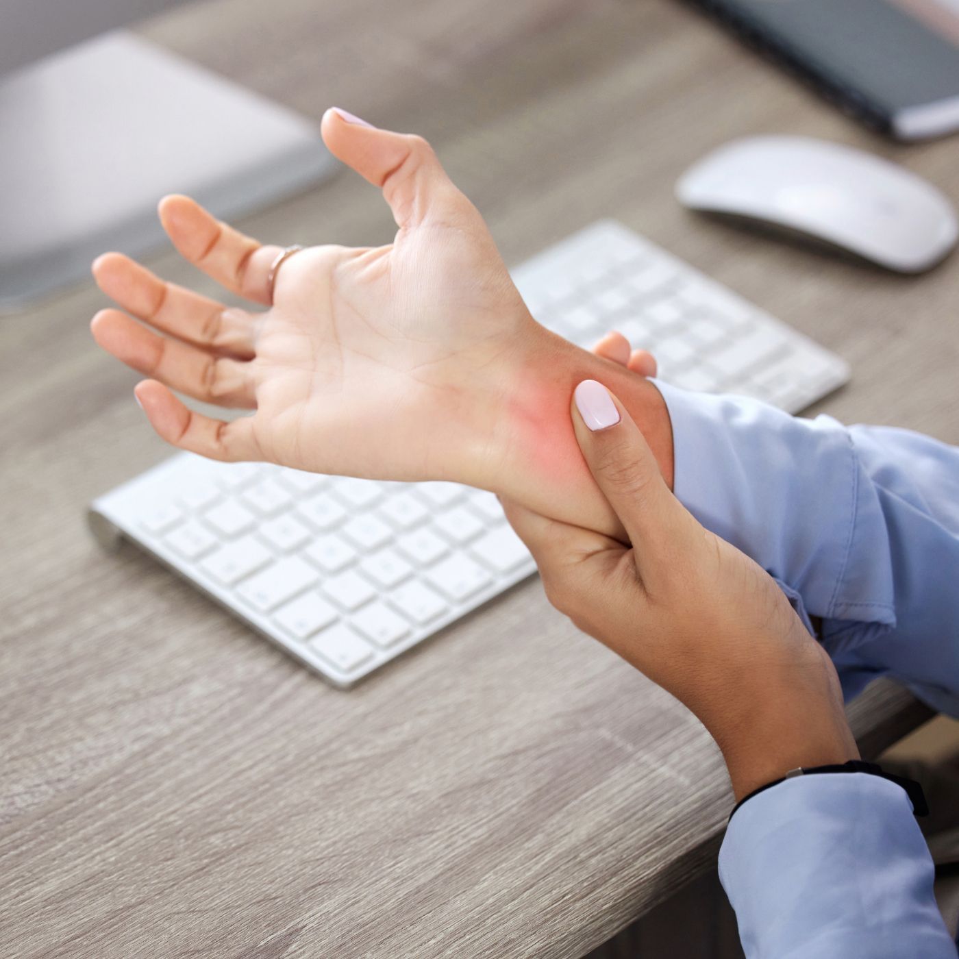 Person applying cream to a wrist with a visible rash beside a keyboard and mouse on a desk