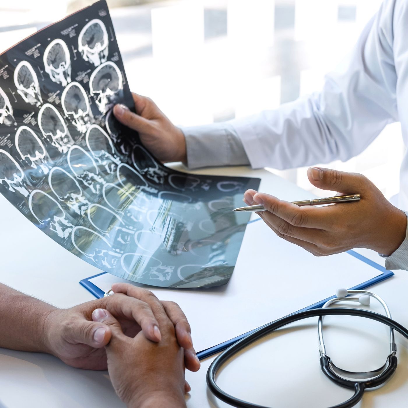 Doctor reviewing brain scan with a patient in a bright clinic, stethoscope on desk