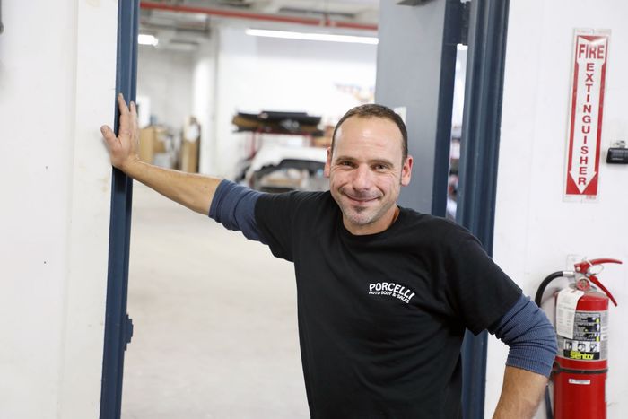 A man leaning against a door with a fire extinguisher in the background