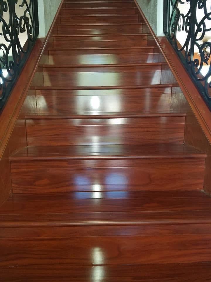 Polished wooden staircase with ornate black railings on both sides