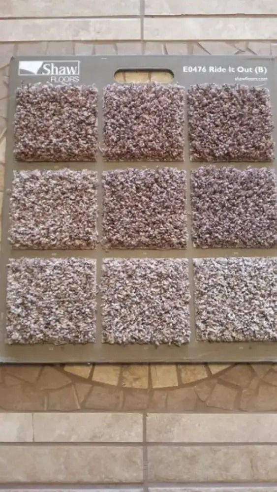Display board with nine square samples of speckled brown and gray carpet or tile patterns.