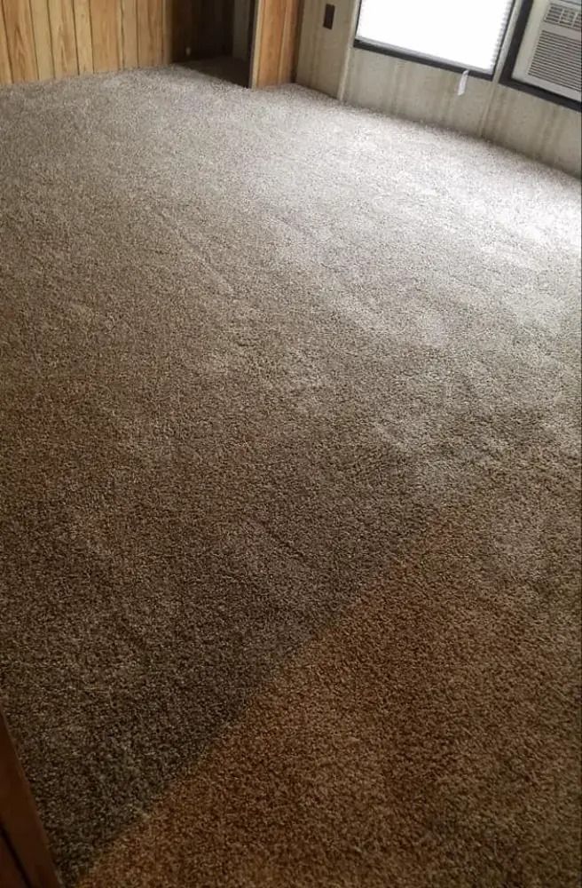 Empty beige carpeted room with windows and wood-paneled walls