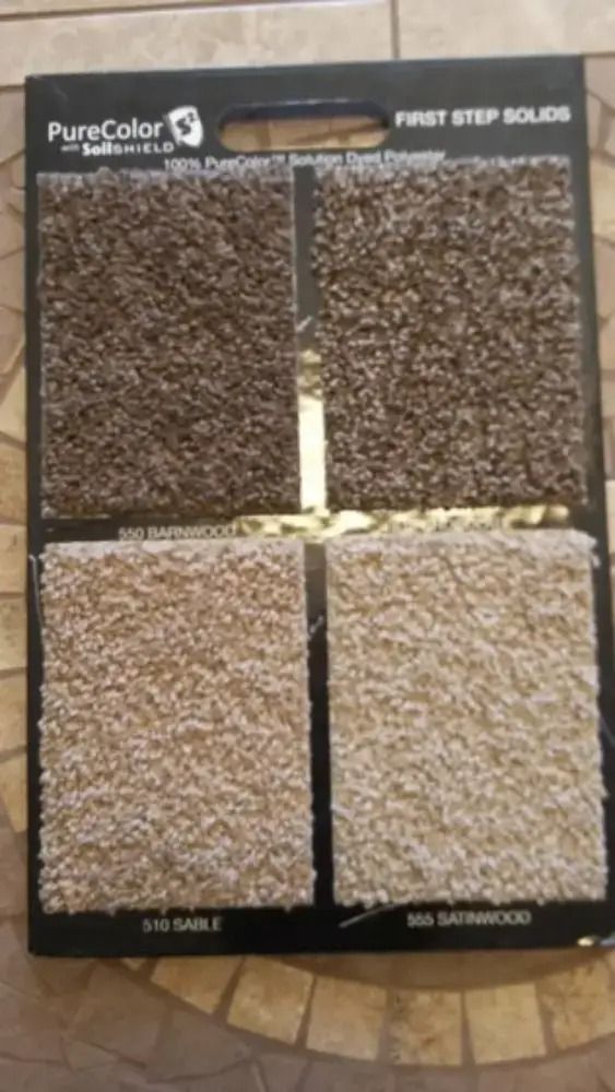 Sample board showing four shades of brown carpet or flooring textures in a store display