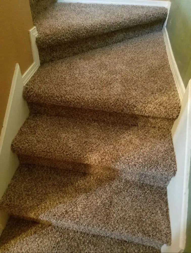 Carpeted staircase with a loose, wrinkled runner on the steps.