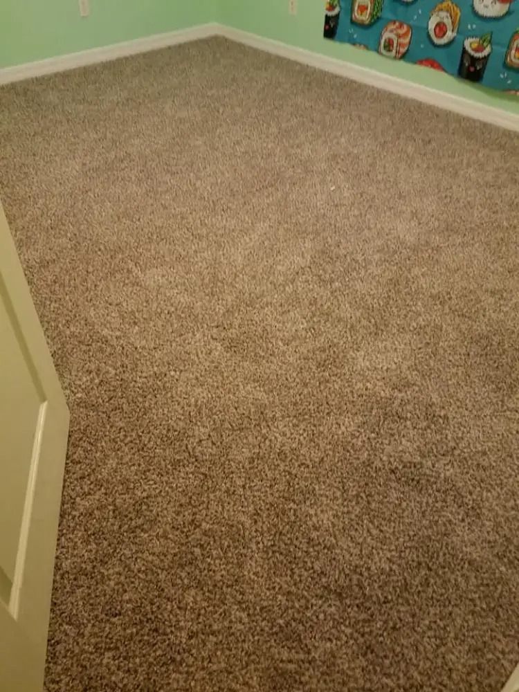 Empty beige-carpeted room with mint green walls and a colorful curtain along the right side.