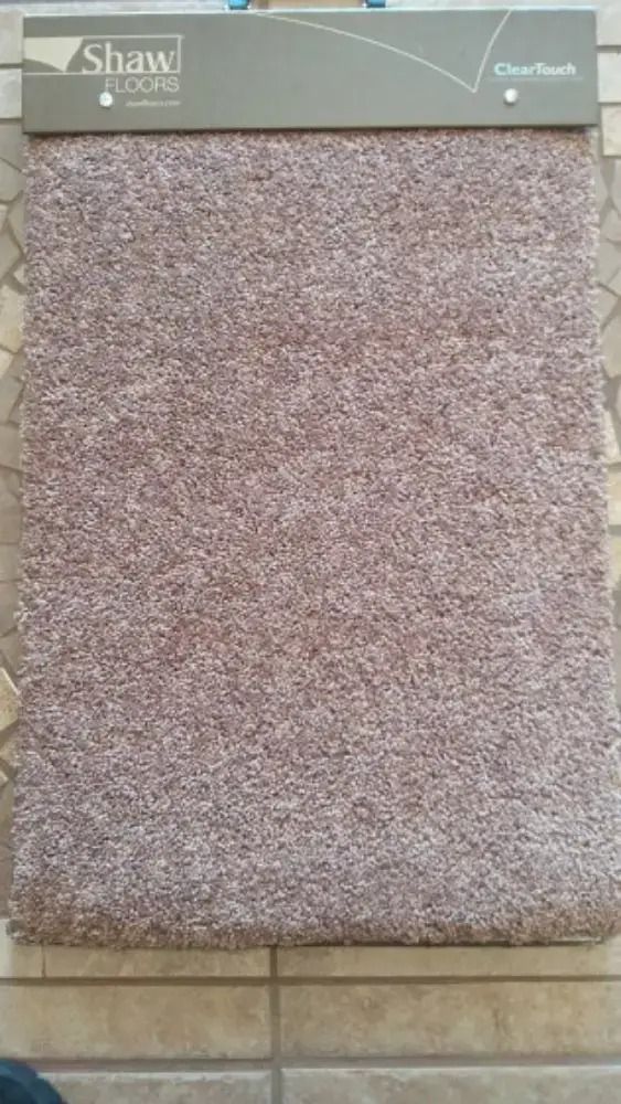 Rolled speckled beige carpet sample displayed on a wall rack