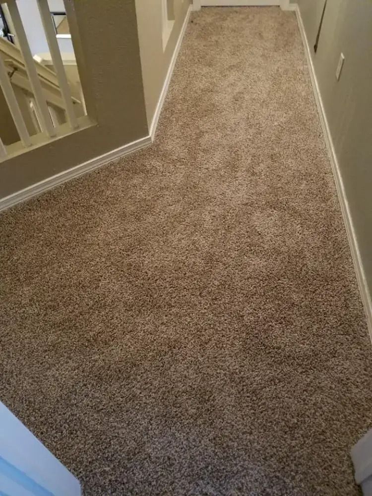 Carpeted hallway with beige walls and a staircase railing on the left