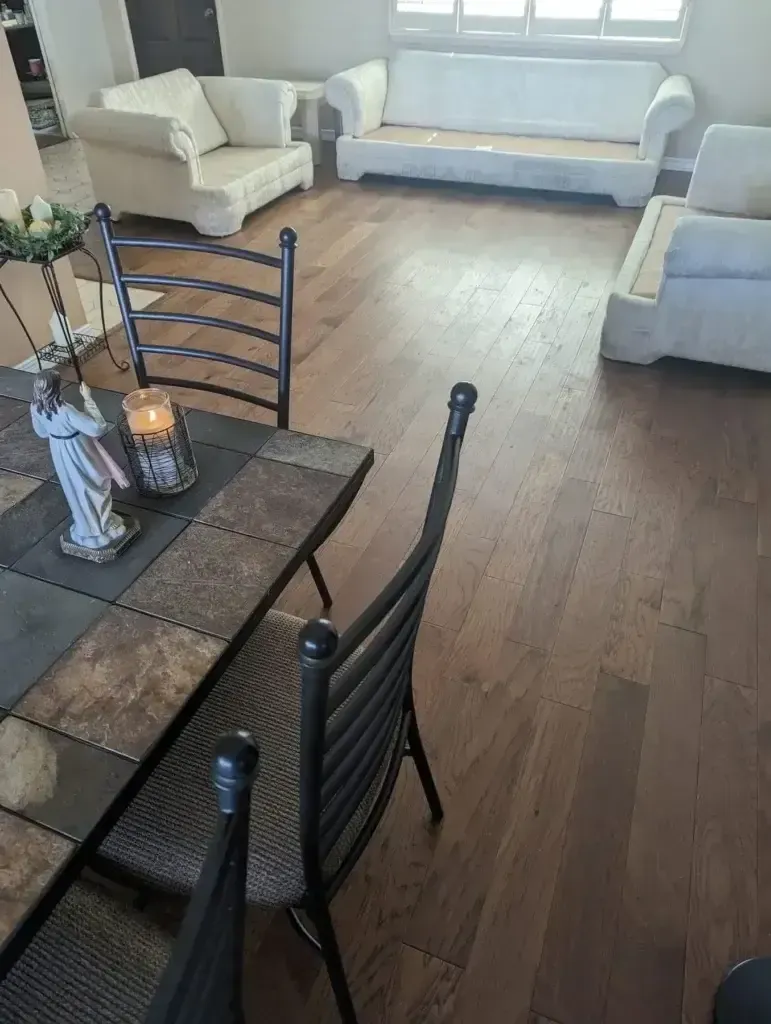 Living room with beige sofas, wood floor, and dining table with candles in foreground