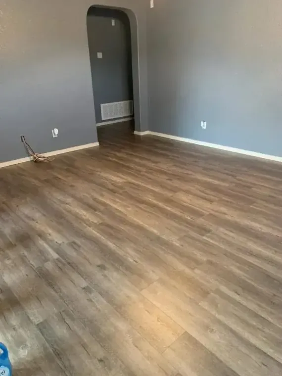 Empty room with gray walls, wood-look flooring, and a doorway.