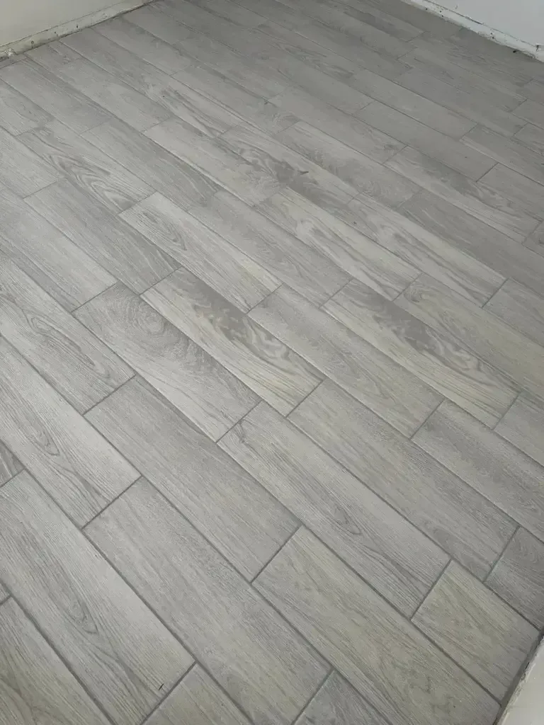 Gray wood-look tile flooring viewed at an angle, showing a clean indoor surface.
