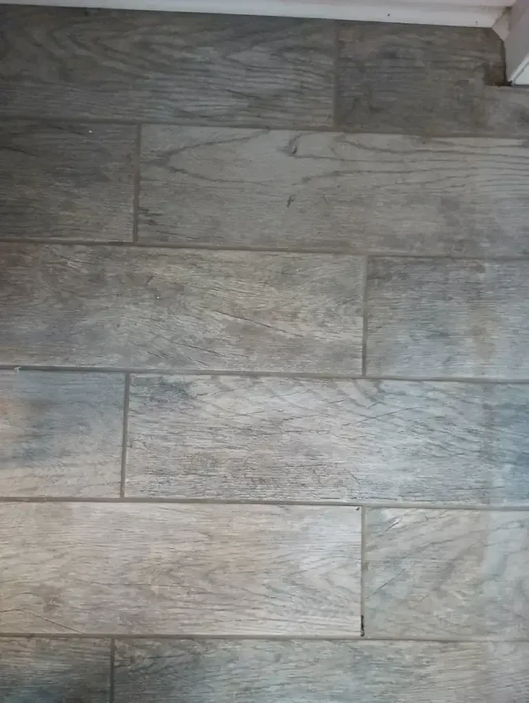 Gray wood-look plank flooring with a white baseboard at the top edge