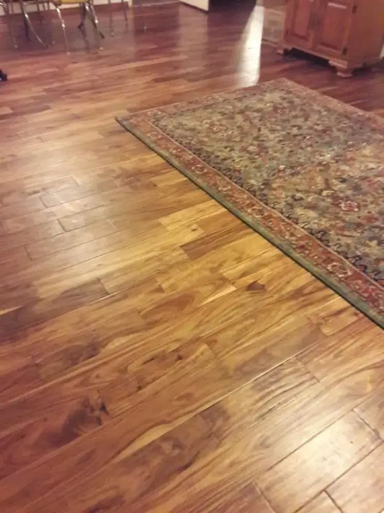 Shiny wooden floor with a patterned area rug in a warmly lit room