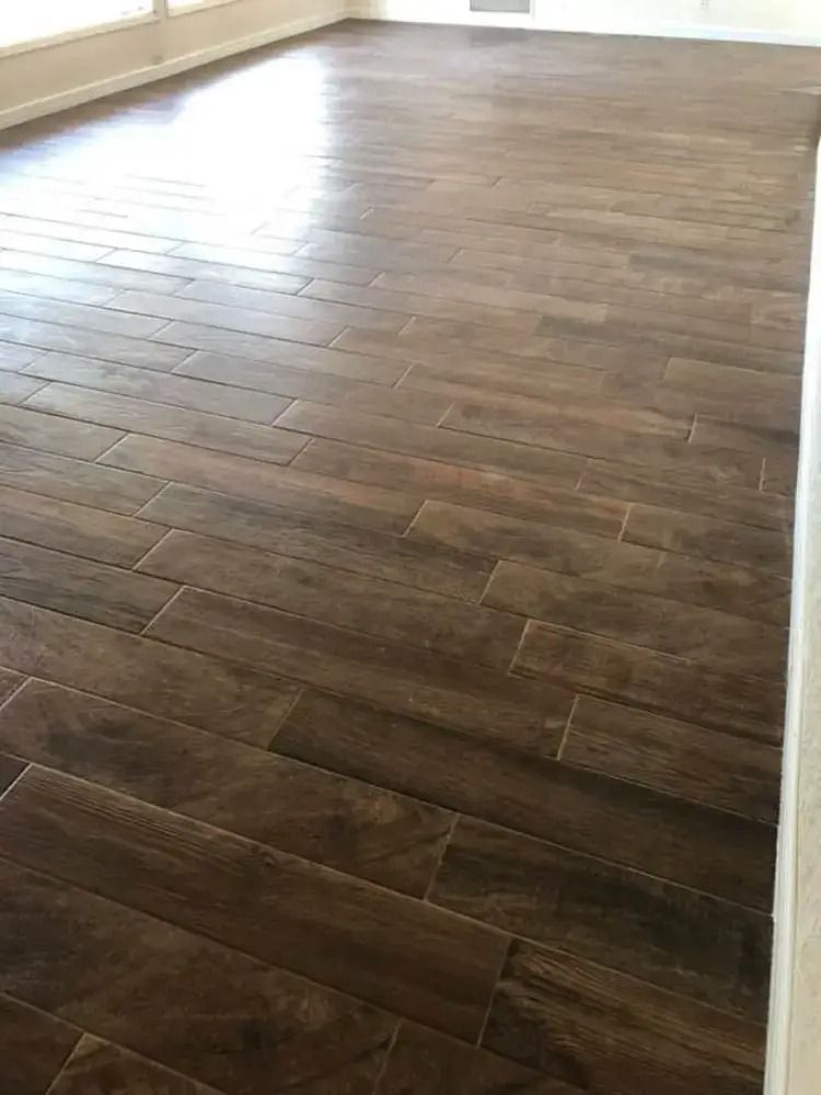 Dark wood-look plank flooring in an empty room, viewed from a low angle.